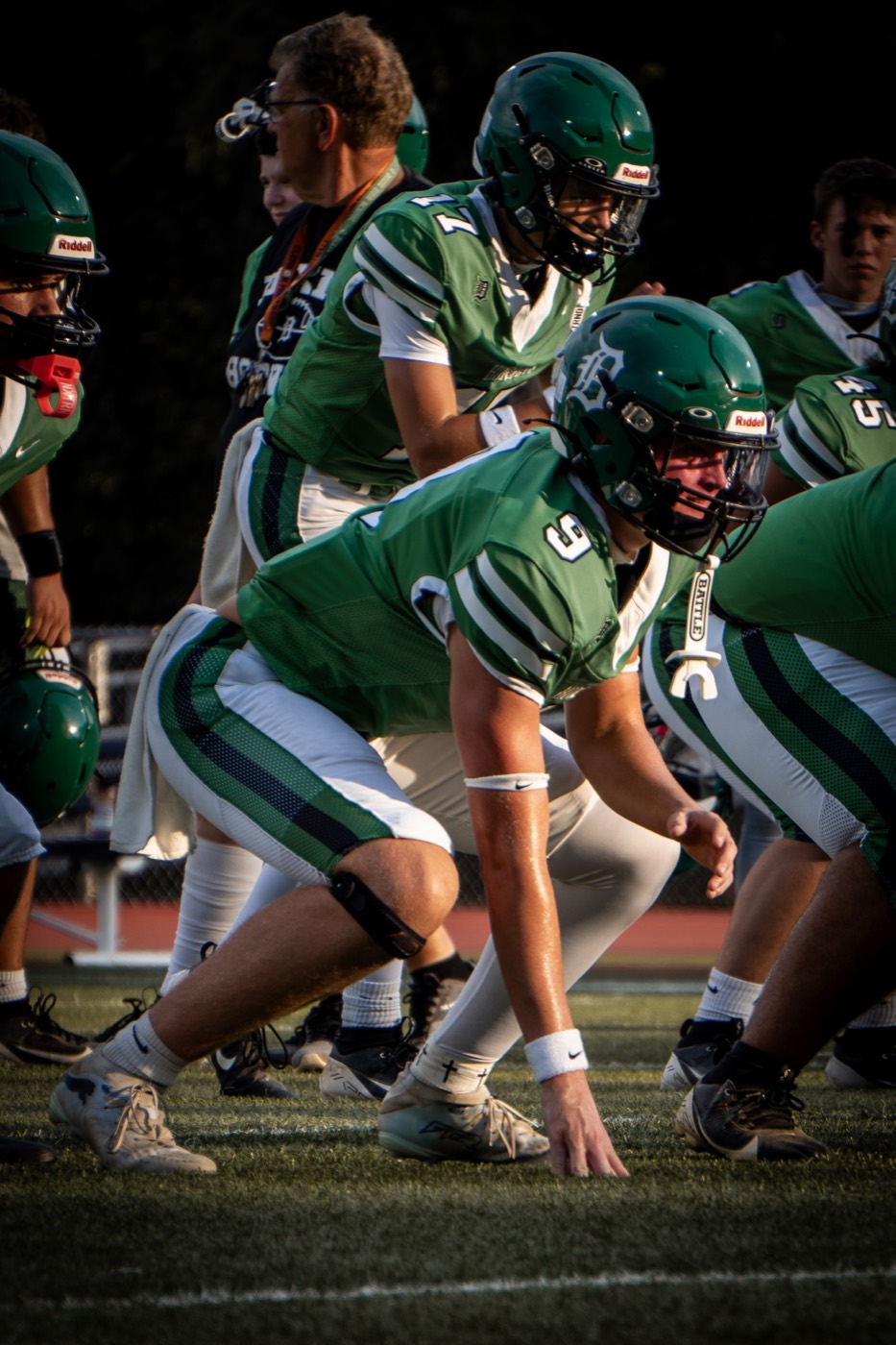 Dixie Hornets offensive line set at the snap under stadium lights