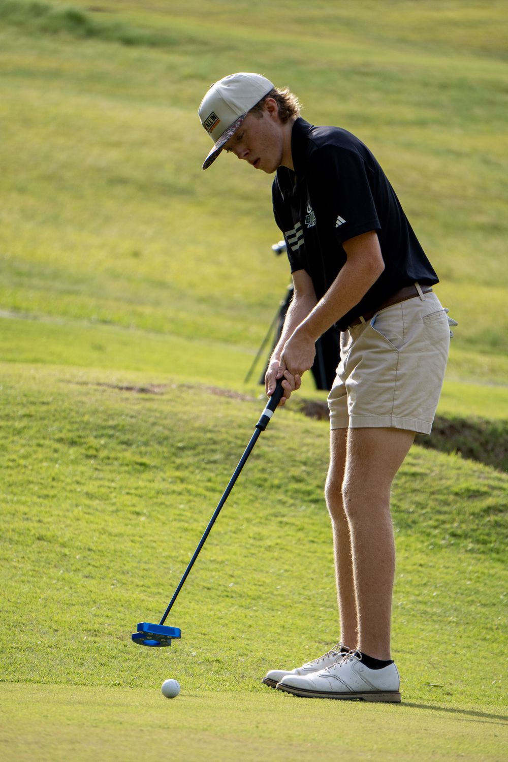 Golfer lining up a putt on the green during a high school golf match